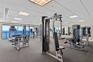 A gym with various exercise equipment, large windows, and a view of the ocean. - Beachfront condo with balcony view & pool - snowbird-friendly (Panama City Beach)