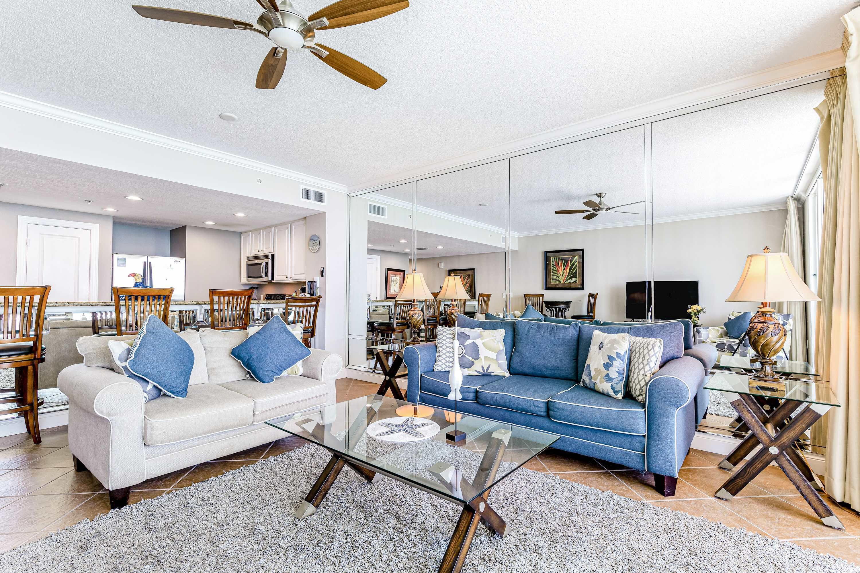 A spacious living room with a sofa, coffee table, and a ceiling fan.