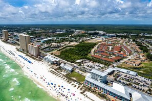 An aerial view of a coastal city with a beach, hotels, and a large commercial building. - Resort condo with putt-putt, gym, pools, hot tub, tennis, & beach access (Panama City Beach)