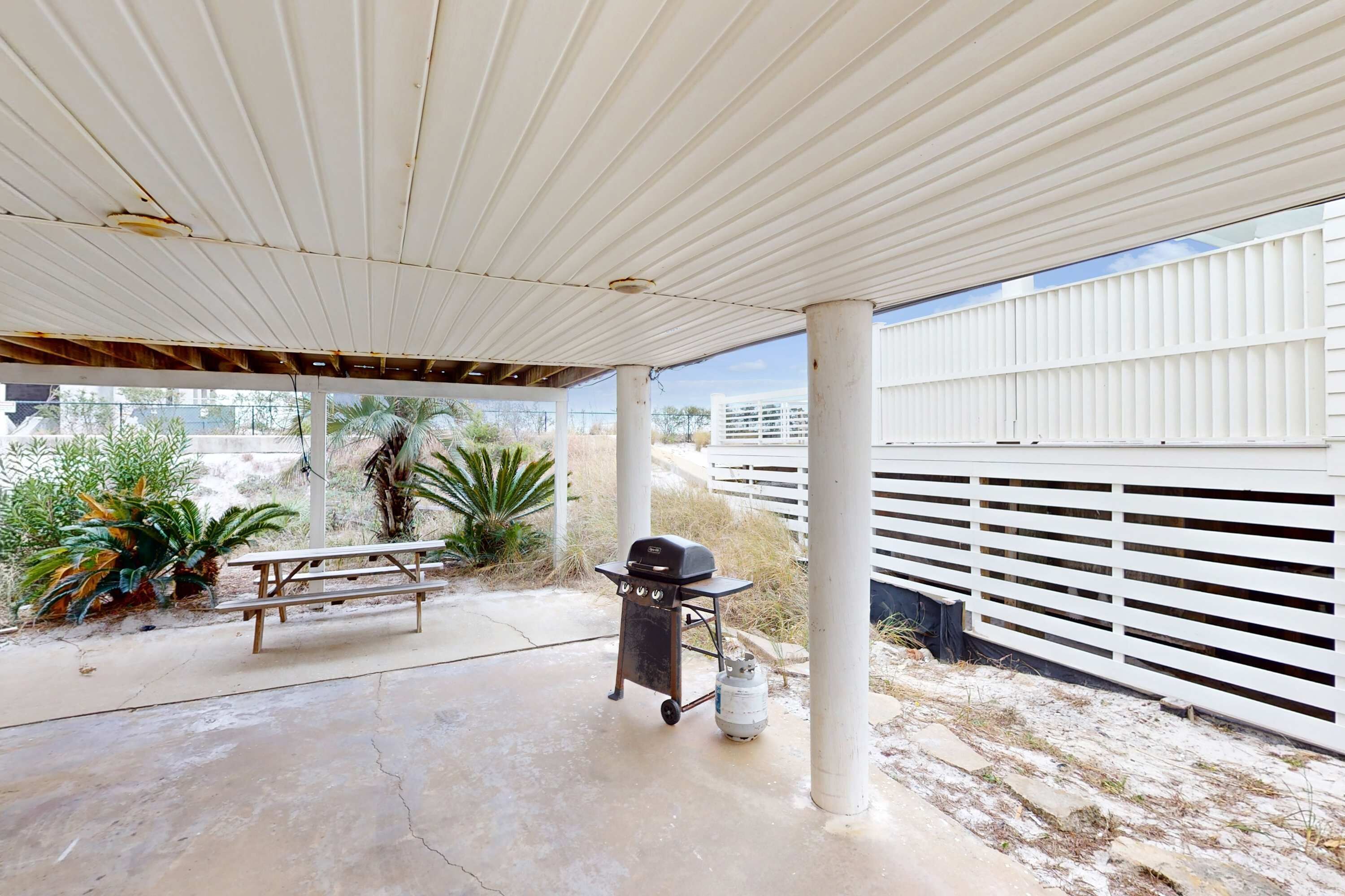 An outdoor patio area with a grill, a picnic table, and a water dispenser.