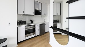 A modern kitchen with white cabinetry, a microwave, a coffee machine, and a dishwasher. - The Flamingo | Sea Point Prom | One Bed | Balcony (Cape Town)