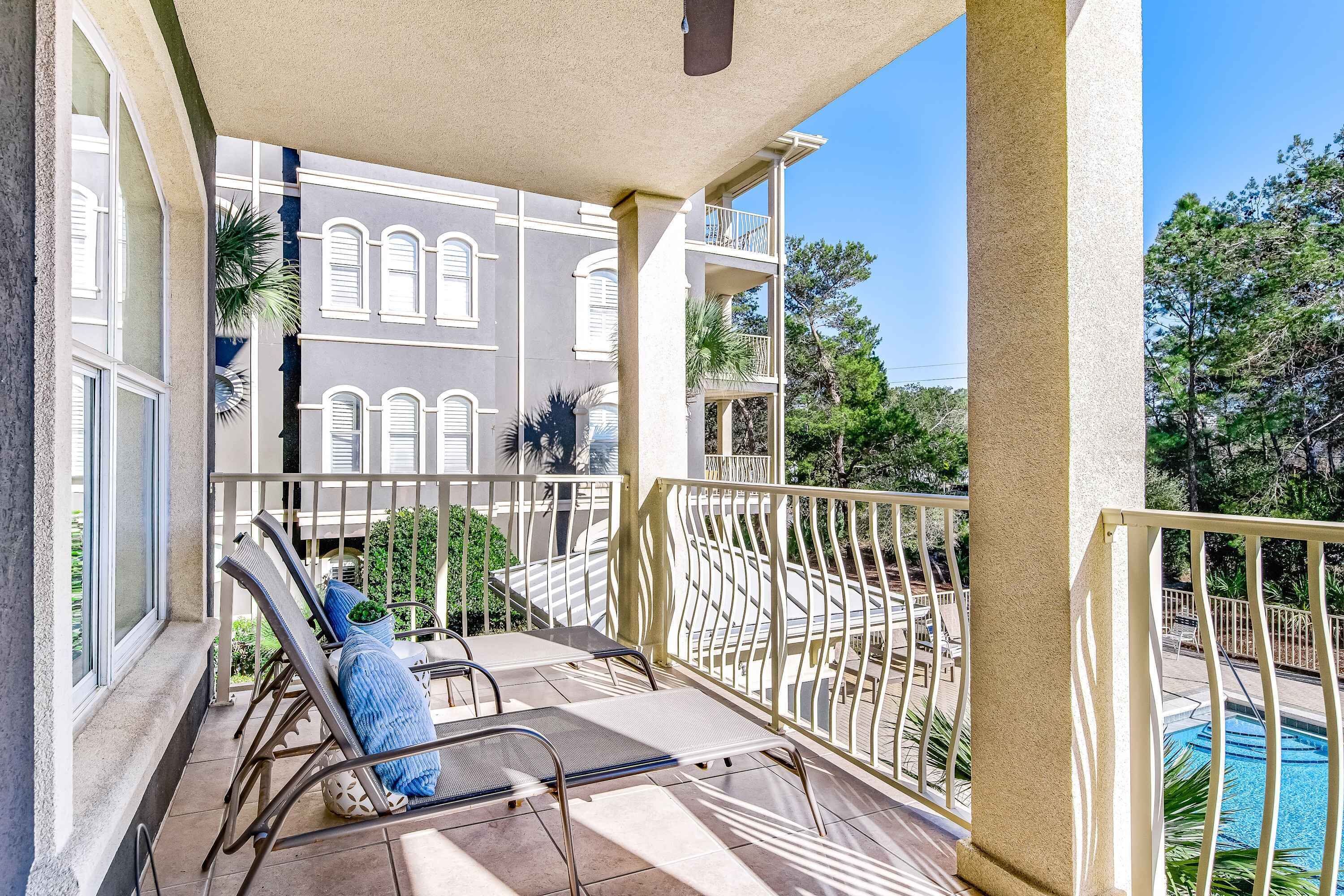Un balcon avec des chaises longues et vue sur une piscine.