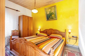 Una habitación con una cama de madera, una mesita de noche con lámpara, un armario y un cuadro en la pared.