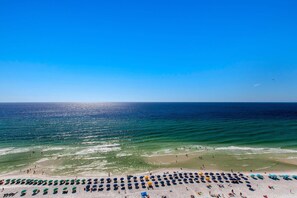 Une plage bordée de rangées de parasols, où les gens profitent du soleil.
