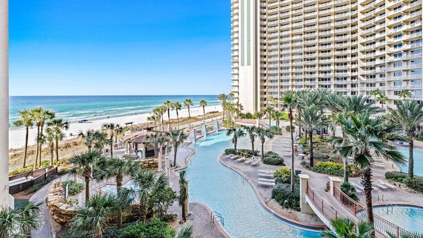 Un resort con piscina, palmeras y vista al mar.
