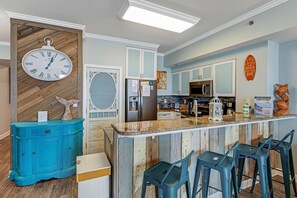 Eine Küche mit Holzrückwand, einer Uhr, einem Kühlschrank und einer Bar mit Hockern.
