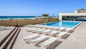 A pool area with lounge chairs and a view of the ocean. - 16th floor condo with shared on-site pools, hot tub, restaurant, and bar (Destin)