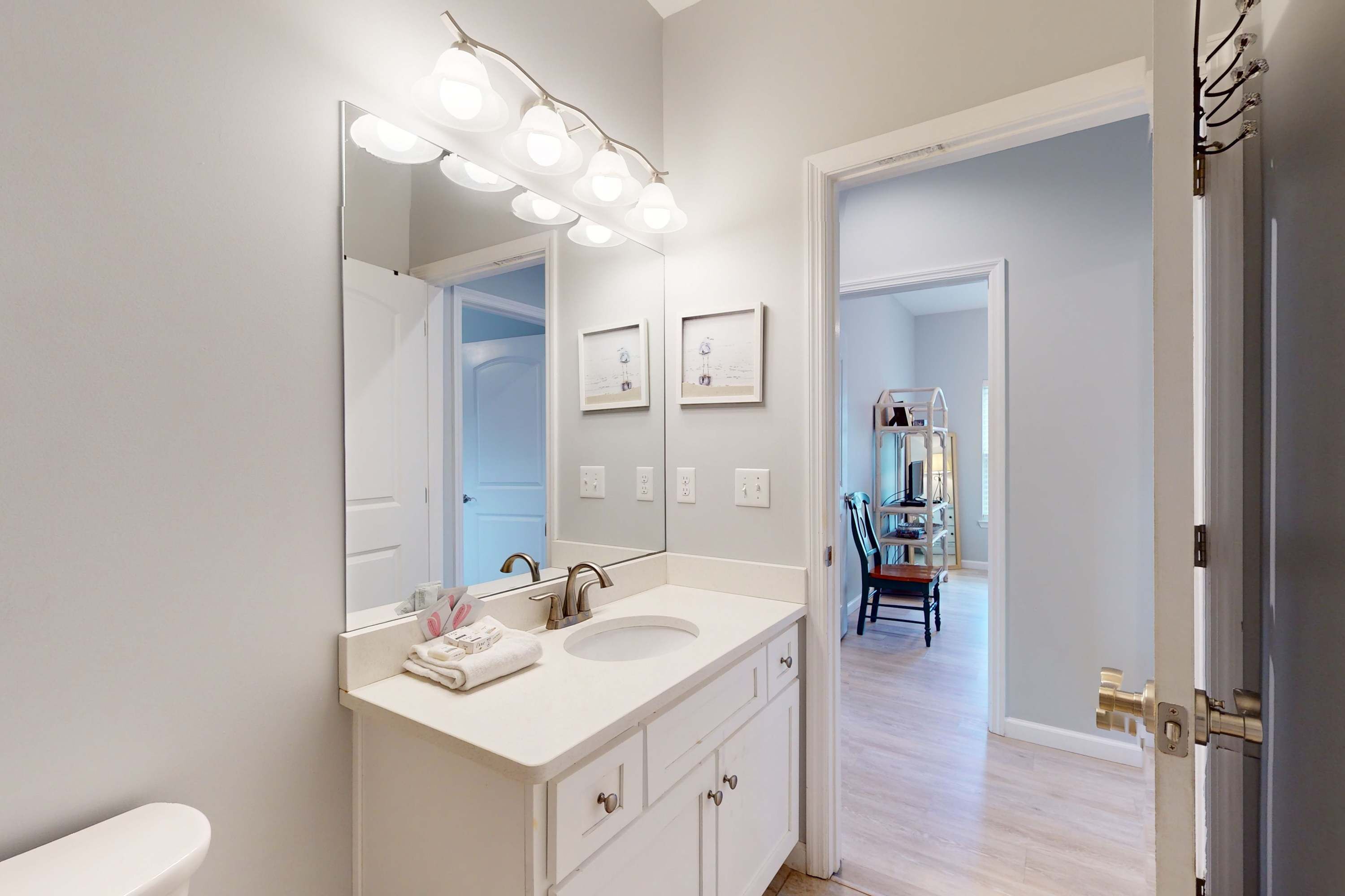 A bathroom with a white vanity, a large mirror, and a lighted vanity area.