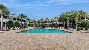 Uima-allas, jonka ympärillä on aurinkotuoleja ja palmuja, ja taustalla näkyy hotellirakennuksia.