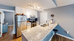A modern kitchen with stainless steel appliances, a marble countertop, and a built-in oven. - 2-story house near the beach & ocean with deck, golf cart, washer&dryer, AC (St. George Island)