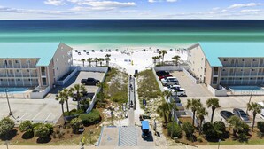 Un hotel sulla spiaggia con una passeggiata centrale, parcheggio e vista sull'oceano.