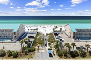 A beachfront hotel with a central walkway, parking, and a view of the ocean. - Three-Story Home w/Washer/Dryer, Gas Grill, Central A/C, & Shared Pool, Hot Tub (Destin)