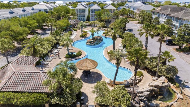 Un resort con piscina, palme e vista sull'oceano.