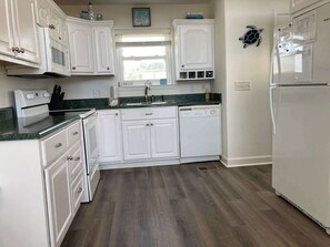 A kitchen with white cabinets, a dishwasher, a stove, and a refrigerator.