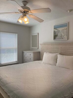 A bedroom with a bed, a ceiling fan, a radiator, a dresser, and a painting on the wall. - Dog-friendly Private home with gulf view, golf cart and easy beach access (Port St. Joe)