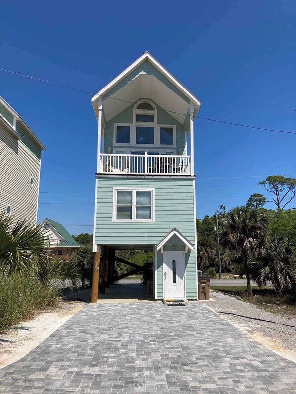 A two-story building with a balcony, a front door, and a small porch. - Dog-friendly Private home with gulf view, golf cart and easy beach access (Port St. Joe)