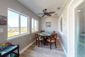 A dining area with a round table, chairs, and a ceiling fan. - Updated home across from beach with firepit, sunroom, & fast WiFi - snowbirds OK (Mexico Beach)