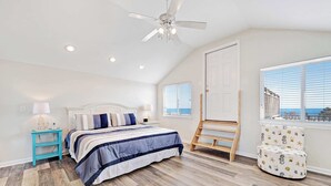 A bedroom with a bed, a ceiling fan, a window with blinds, a wooden ladder, and a patterned chair. - Beachfront home with screened porch with boardwalk access to pool (Cape San Blas)