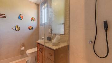 Ein Badezimmer mit Duschkabine, Toilette, Waschbecken mit Handtuch und Wandbildern von Fischen.