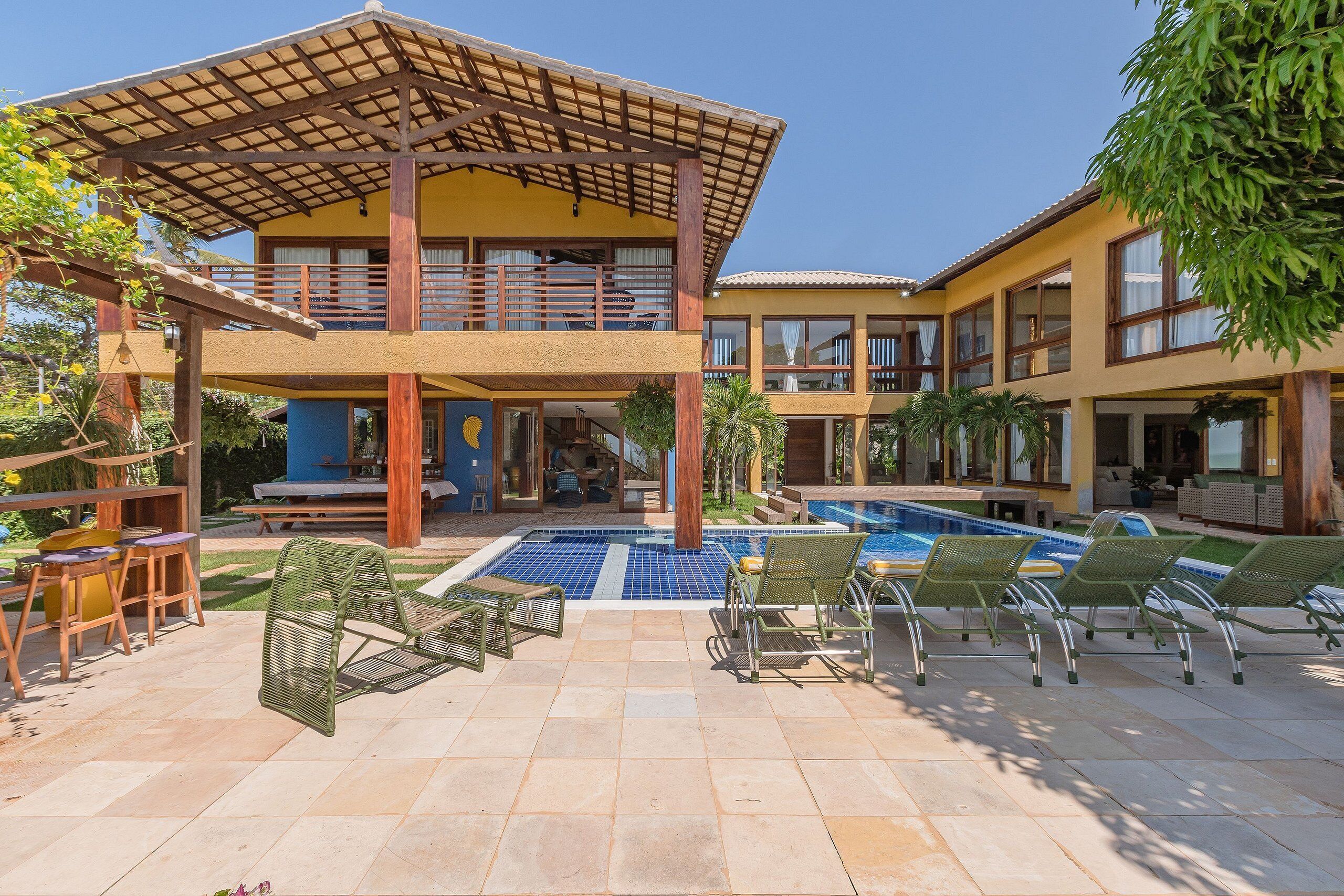 Un bâtiment à deux étages doté d’un espace piscine, de coins salon extérieurs et d’une terrasse couverte.