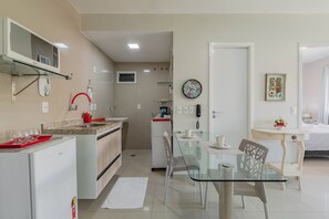 Una cucina moderna con frigorifero, forno a microonde e un piccolo angolo ristoro con un tavolo in vetro e sedie.