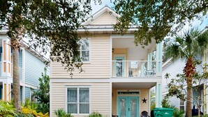 A two-story building with a balcony, a door marked "King Caribbean," and a star decoration. - Large, Open Home, Shared Pool, Bike or Walk to the Gulf (Destin)