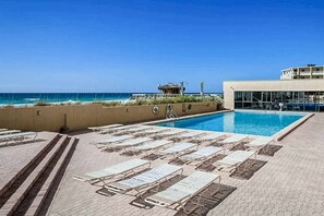 Ein Poolbereich mit Liegestühlen und Blick auf den Ozean.