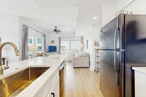 A modern kitchen with a large black refrigerator, white countertops, and a built-in oven. - Gorgeous coastal condo with shared pool and private balcony (Miramar Beach)