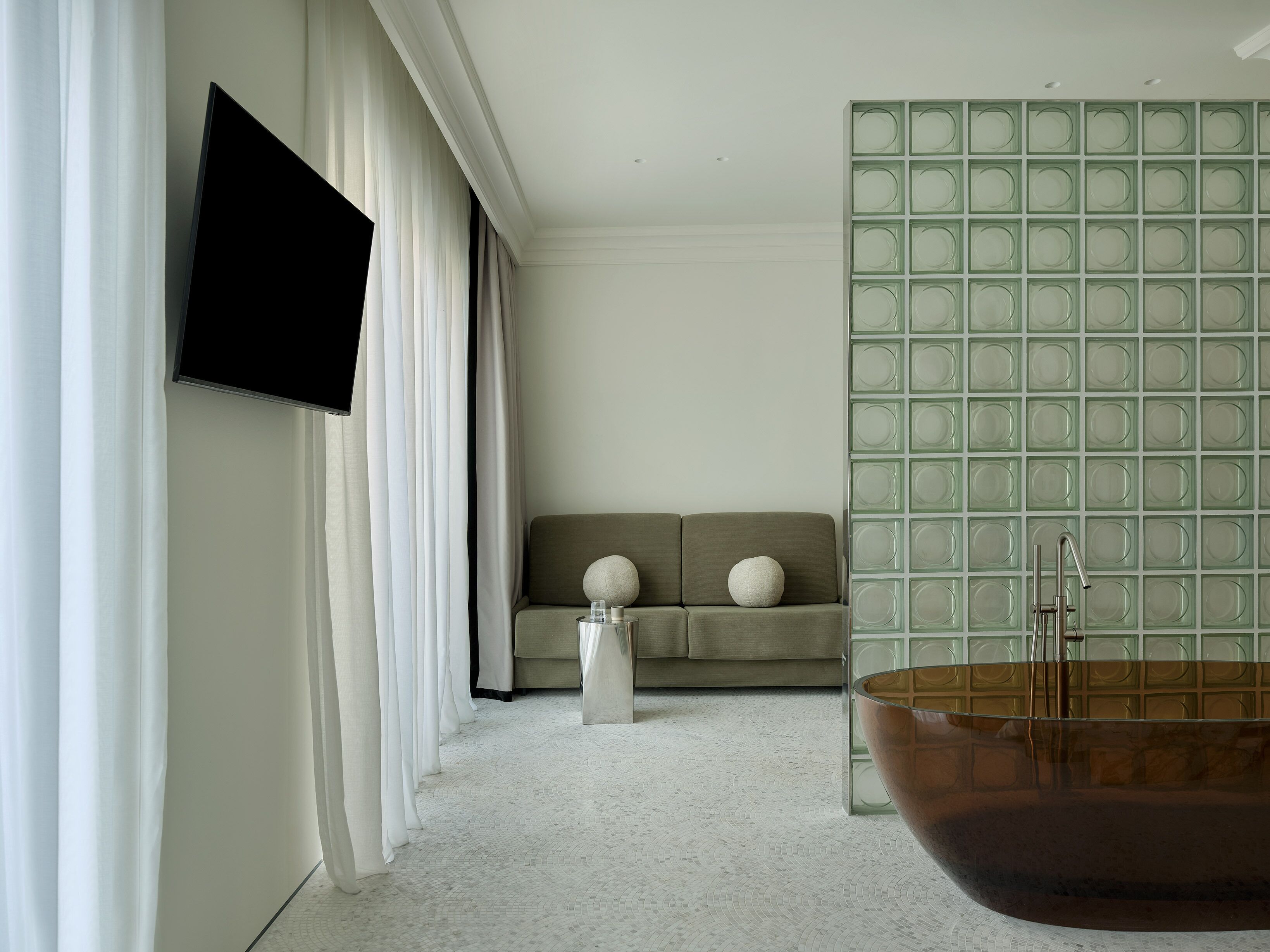 Una sala moderna con un sofá, un televisor de pantalla plana, una mesa de centro y una pared con diseño verde.