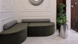 Un interno moderno con un divano angolare curvo, uno specchio decorativo e una pianta in vaso.