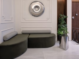 Um interior moderno com um sofá modular curvo, um espelho decorativo na parede e um vaso de planta.