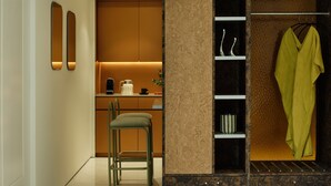 Una cucina moderna con uno sgabello da bar, una macchina per il caffè e un appendiabiti verde.