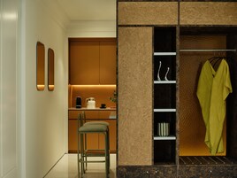 Cocina moderna con un taburete de bar, una cafetera y una prenda verde colgando.