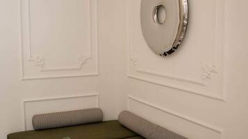 Una habitación con un sofá modular, un espejo redondo y una mesita auxiliar con una planta.