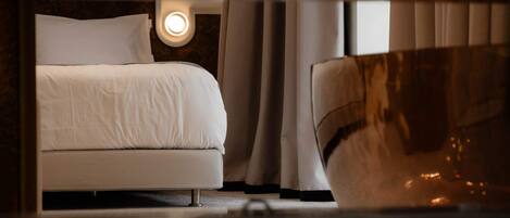 A hotel room with a bed, a nightstand, and a wall-mounted light fixture.
