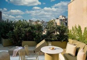 A rooftop terrace with outdoor seating, a round table, and a view of the cityscape. - The Newel Kolonaki (Athens)