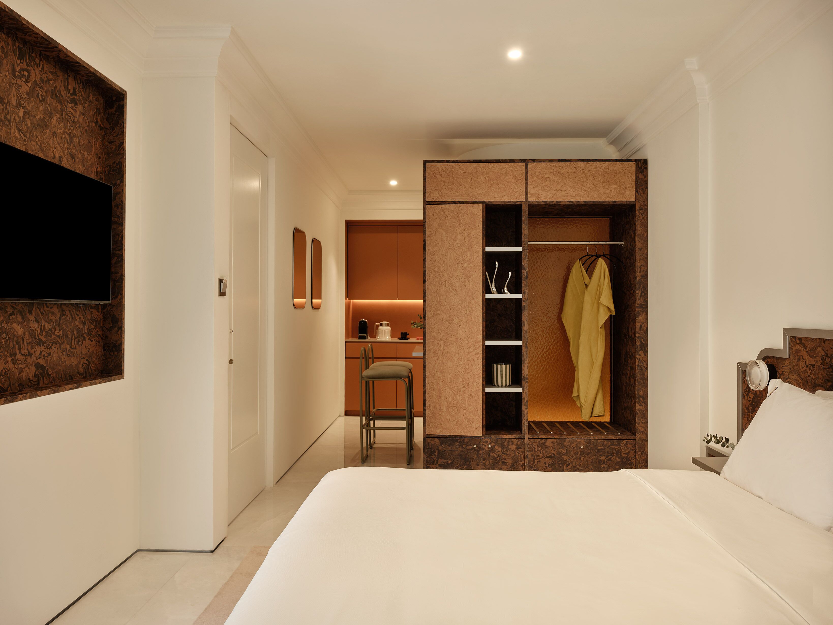 A hotel room with a bed, a wardrobe, a seating area, and a television.