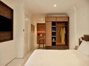A hotel room with a bed, a wardrobe, a seating area, and a television. - The Newel Kolonaki (Athens)