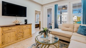 Un salon moderne doté d’un téléviseur à écran plat, de meubles en bois, d’un canapé beige et d’une table basse en verre.