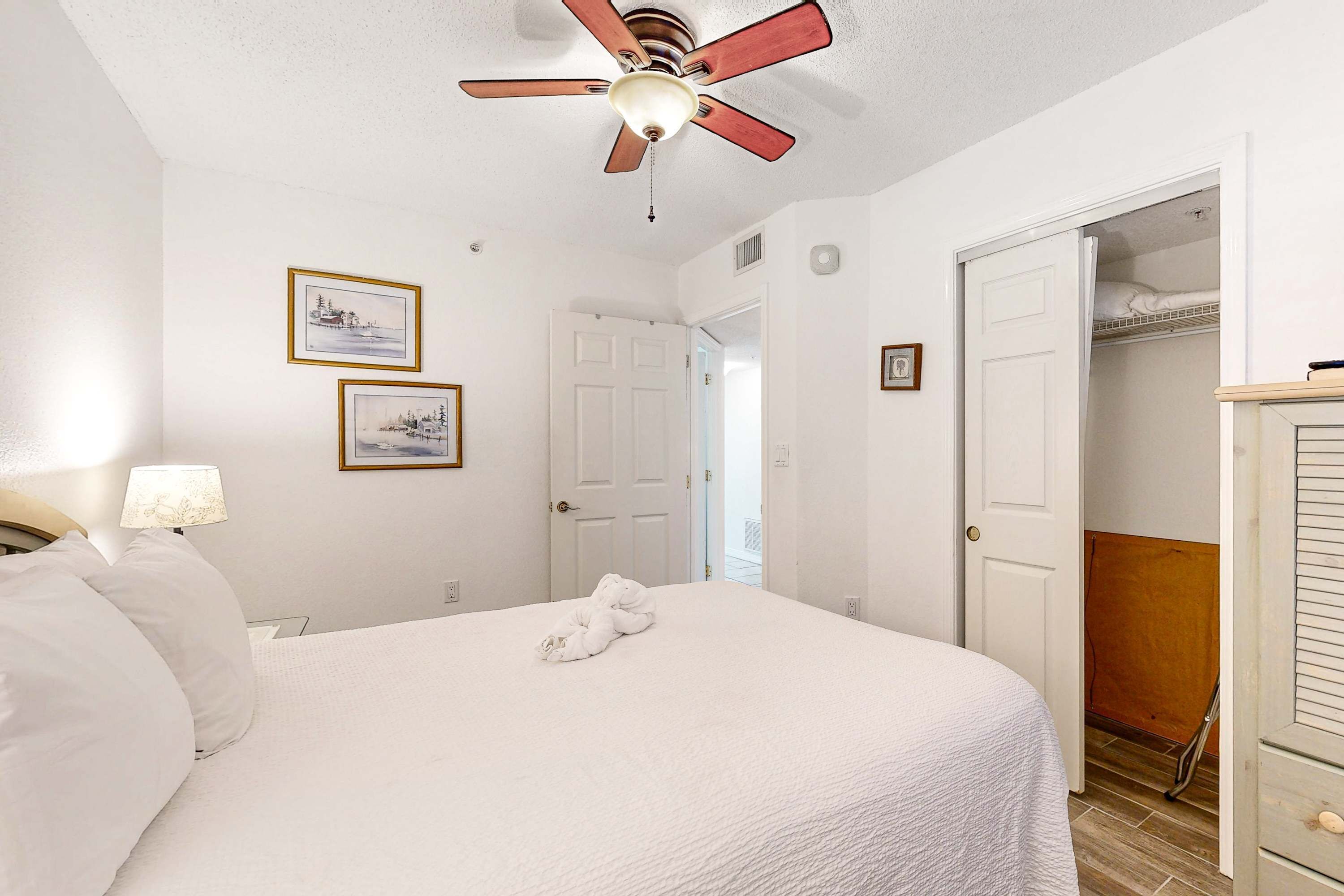 Une chambre à coucher avec un lit, un ventilateur de plafond, une porte et une armoire.