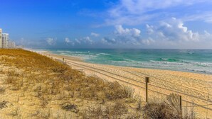 A beach with a sandy shore, a wooden fence, and a clear sky. - Coastal Condo with heated pool, hot tub, tennis, & beach access (Destin)