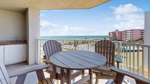 A balcony with a table and chairs, overlooking a beach and a pool area. - Inlet Reef 414 (Destin)