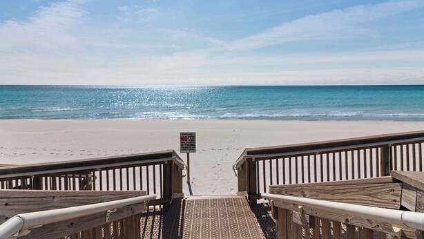 A wooden boardwalk leading to a beach with a sign prohibiting littering. - Inlet Reef 414 (Destin)