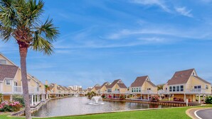 A waterfront property with a canal, houses with balconies, and a palm tree. - Inviting condo with dock, pool, hot tub & private beach - dog-friendly (Destin)