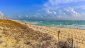 A beach with a sandy path, ocean waves, and a clear sky. - Inviting condo with dock, pool, hot tub & private beach - dog-friendly (Destin)