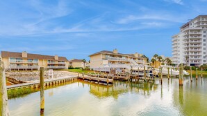 A waterfront hotel with multiple balconies, a dock, and a marina. - Inviting condo with dock, pool, hot tub & private beach - dog-friendly (Destin)