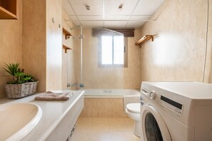 A modern bathroom with a bathtub, a washing machine, and a shower. - Holiday Home 'Oliva' with Sea View, Wi-Fi and Air Conditioning (Almuñécar)