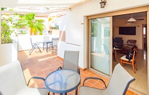 A patio with a table and chairs, a glass door leading to an interior room, and a palm tree. - Holiday Home 'Oliva' with Sea View, Wi-Fi and Air Conditioning (Almuñécar)