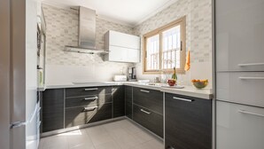 Et moderne køkken med mørke skabe, hvide bordplader, et vindue og en indbygget ovn.