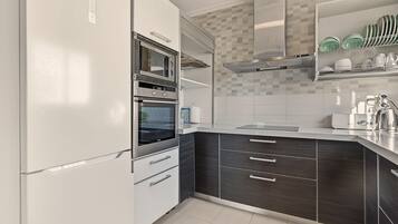 Una cocina moderna con horno empotrado, microondas y campana extractora de acero inoxidable.